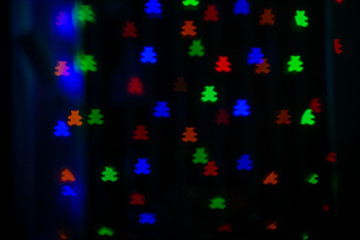 Beautiful bokeh in the form of bears of different colors on a dark background