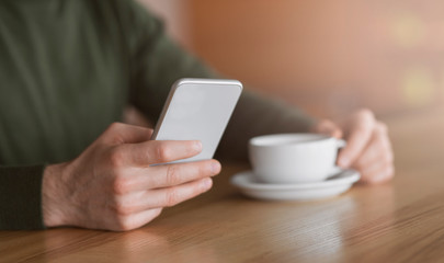 Cropped of man holding smartphone and cup of coffee