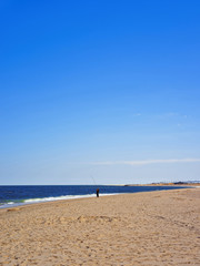 Man fishing along Atlantic Ocean shore at Sandy Hook