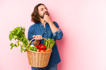 Young man picking organic vegetables from his garden isolated looking sideways with doubtful and skeptical expression.