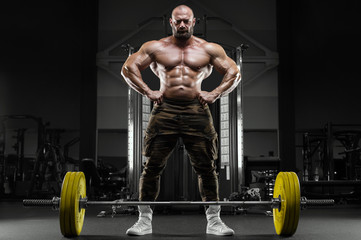 Fototapeta na wymiar Bodybuilder strong athletic man pumping up muscles