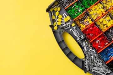 Tips of different sizes and colors for crimping stranded electrical wires. Wire tips in the box on a yellow background