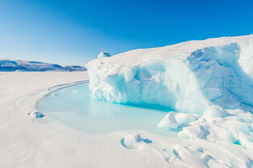 Fototapeta na wymiar Ice berg on frozen sea in sunshine. Greenland