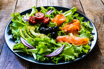 Salmon salad - smoked salmon and vegetables on black stone background