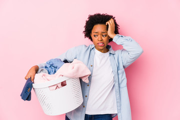 Middle age african american woman doing laundry isolated being shocked, she has remembered...