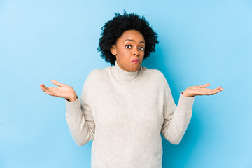 Middle aged african american woman against a blue background isolated confused and doubtful...