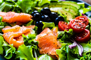 Salmon salad - smoked salmon and vegetables on black stone background
