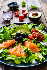 Salmon salad - smoked salmon and vegetables on black stone background