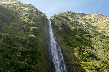 waterfall on cliff side with sky and vegetation