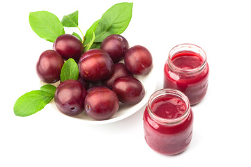 Violet fresh ripe plums and a glass with a puree from plums, background