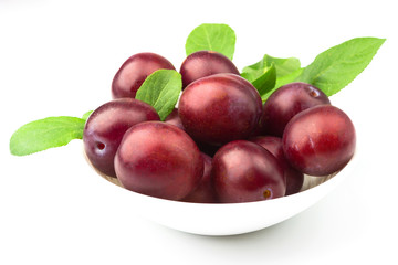 Violet fresh ripe plums in the white plate, light background