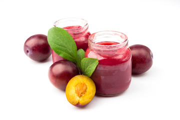 Violet fresh ripe plums and a glass with a puree from plums, background