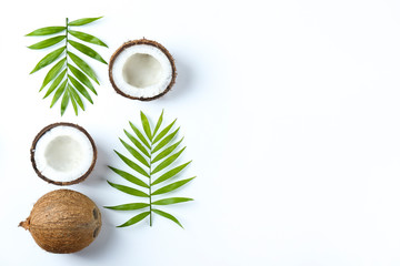 Top view shot of coconuts, whole and cracked on halves on paper textured background with a lot of...