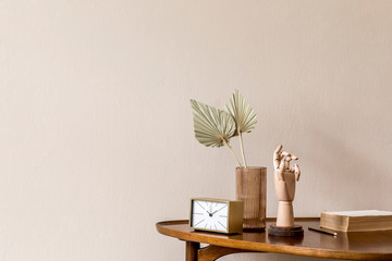 Stylish composition on the design wooden table with gold clock, wooden hand and paper flowers in vase. Beige background walls. Minimalistic conept of living room. Copy space. Template. 