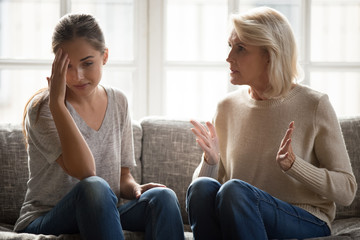 Annoyed mature retired mother telling complaints to daughter.