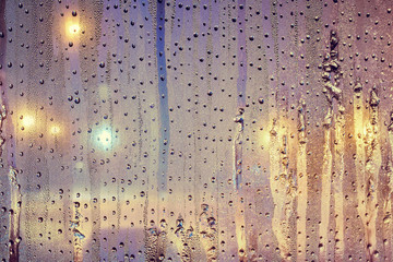 Window with drops of condensate late in the evening with street lighting in the dark. Wet transparent glass background. Droplets pattern.