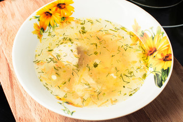 Appetizing chicken soup in deep plate on wooden board.