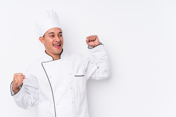 Young latin chef man isolated raising fist after a victory, winner concept.