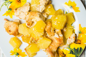 Fried chicken with potatoes on plate on kitchen table.