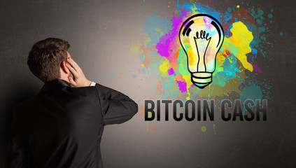 businessman drawing colorful light bulb with BITCOIN CASH inscription on textured concrete wall, new business idea concept