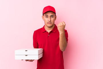 Young pizza delivery latin man isolated showing fist to camera, aggressive facial expression.