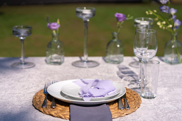 Decorative decoration of the festive table. Glass vases and fresh flowers. Decoration of holidays in the open air