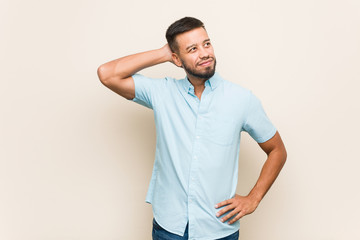 Young south-asian man touching back of head, thinking and making a choice.