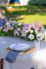 Decorative decoration of the festive table. Glass vases and fresh flowers. Decoration of holidays in the open air