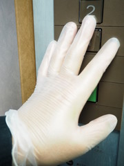 ウイルス付着を防ぐためゴム手袋をしてエレベーターのボタンを押す人