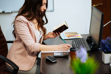 young conceived business brown-haired woman with long hair sits at his desk on an office chair,...