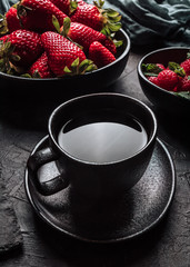 Still life with a bowl of strawberries, a bowl of raspberries, a cutting board and a cup of tea