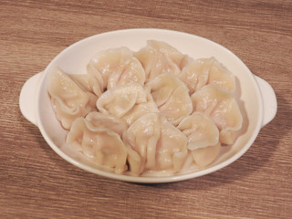 Top view of delicious hot boiled dumplings on white plate on wooden background .Boiled dumplings are traditional Asian homemade food. Taiwan food.