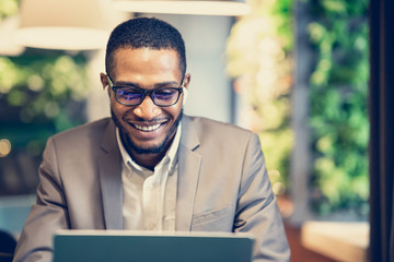 Smiling afro guy in glasses listening to music at office