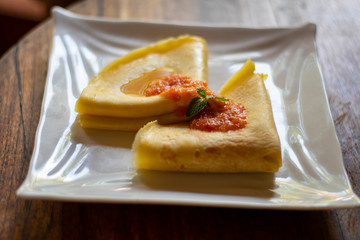 Thin folded pancake served on the table with tomato sauce in a plate for tourists in Bali,
