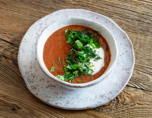 a bowl of pureed beetroot soup with herms and sour cream on wooden background