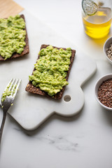 Healthy Snack from Wholegrain Rye Crispbread Crackers with Avocado on white marble background with copy space