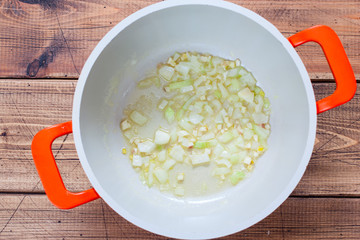 Step-by-step preparation of mashed potato soup with croutons, step 3 - frying chopped onions and garlic for soup, top view, horizontal