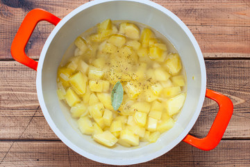 Step-by-step preparation of mashed potato soup with croutons, step 5 - adding chopped potatoes, spices and bay leaves, top view, horizontal