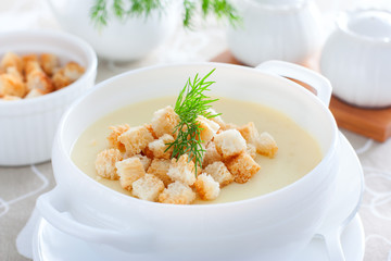 Mashed potato soup with homemade croutons in a white soup plate, horizontal