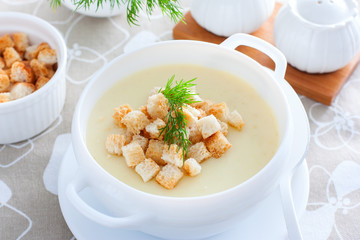 Mashed potato soup with homemade croutons in a white soup plate, horizontal