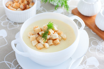 Mashed potato soup with homemade croutons in a white soup plate, horizontal