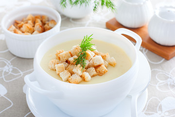 Mashed potato soup with homemade croutons in a white soup plate, horizontal