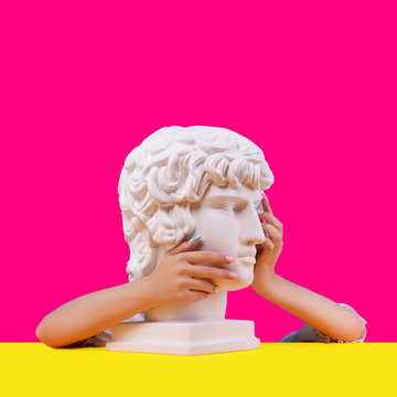 Gypsum statue of Antinous head. Creative. Plaster statue of Aphrodite's head in women hends  . On a abstract background.