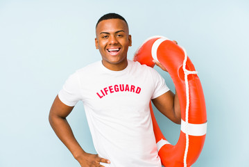 Young latin life guard isolated on blue background laughing and having fun.