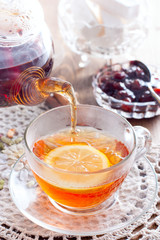 Black tea with cinnamon and lemon in a glass cup on a wooden table, selective focus