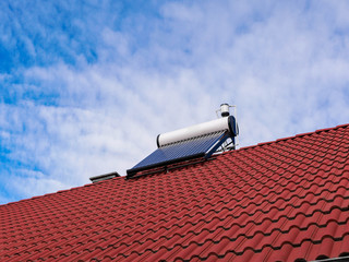 Solar water heater boiler on rooftop, blue sky with white clouds , copy space.