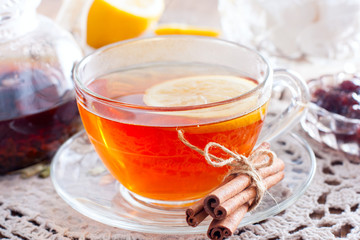 Black tea with cinnamon and lemon in a glass cup on a wooden table, horizontal