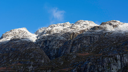 Blue sky above snowcapped mountain peaks on beautiful day in Glencoe,Scottish Highlands,UK.Panoramic landscape scene with copy space and no people.Popular travel destination and ski resort.