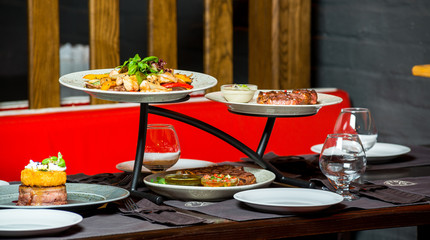 Close up of severed table with different food and dish, meat, fruits, fish in restaurant.