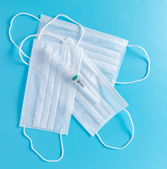 Medical mask and syringe isolated on a blue